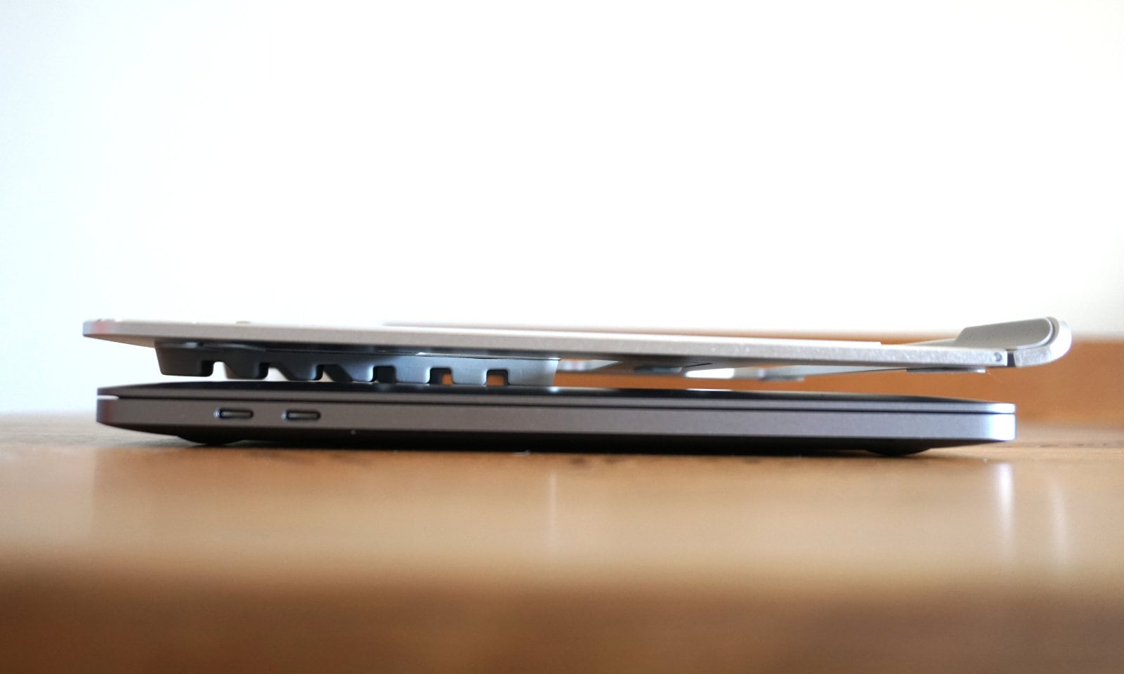 MacBook Proの上に折りたたんだノートPCスタンドを乗せた写真。厚さの比較