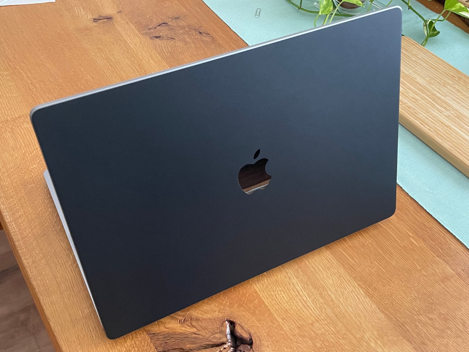 スクリーンを開いた状態のMacBook Pro 16インチをAppleロゴの見える方から撮った写真。マットな黒で覆われた表面だが、Appleロゴ部分には切り抜きが入っているため綺麗に反射している